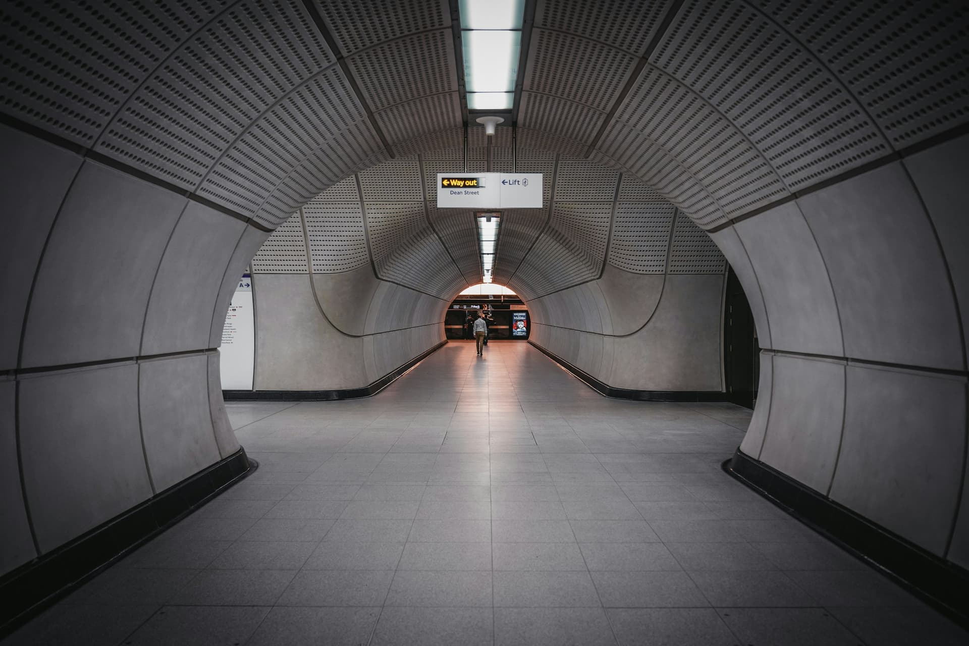 A curved concrete passage on the Elizabeth line, London, lit end to end.