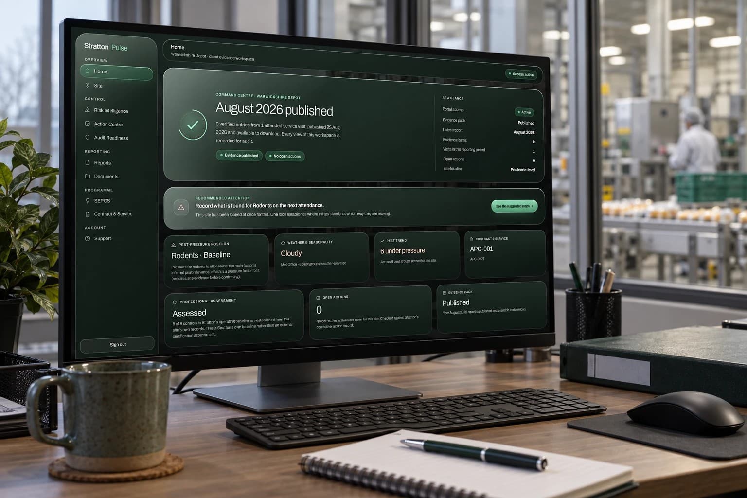 Stratton Pulse open on a desktop monitor in a site office: the Home view for a depot, with the August 2026 period published, no open actions, and panels for pest pressure, weather, pest trend, contract, professional assessment and the evidence pack.