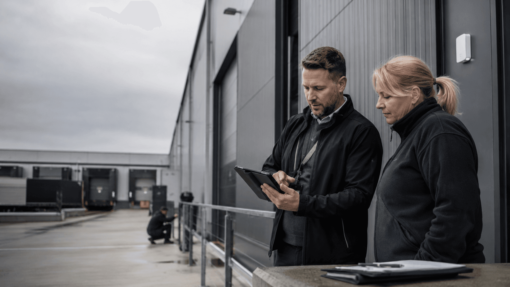 Two Stratton staff reviewing a site record outside a row of loading bays.